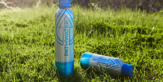 Front view of PATHWATER aluminum water bottles showcasing blue PATHWATER logo and refillable aluminum finish on sunlit grass