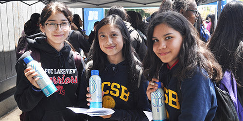 Three students holding reusable PATH Water bottles at an outdoor school event