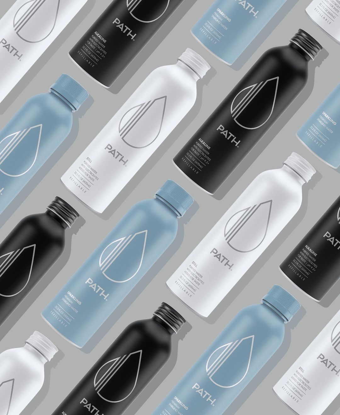 Angled flat-lay of aluminum bottled water showcasing reusable blue, white, and black PATH bottles on gray background