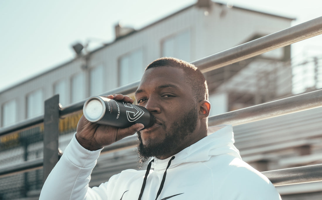 Man drinking from a black PATH bottle on outdoor stadium bleachers