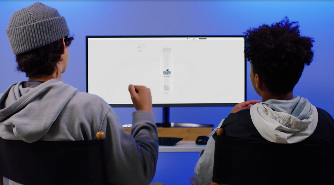 Two people seated watching a desktop monitor displaying a custom PATH bottled water product page against a blue-lit background