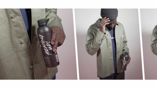 Man in olive jacket holding a black PATH reusable water bottle customized with a white "HEATING UP!" decal in a studio setting