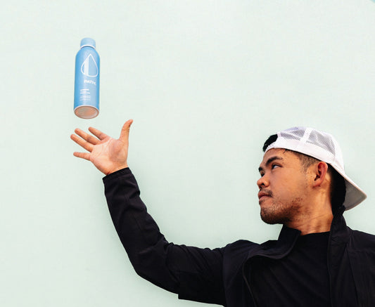 Man tossing a light blue PATH water bottle against a pale mint background
