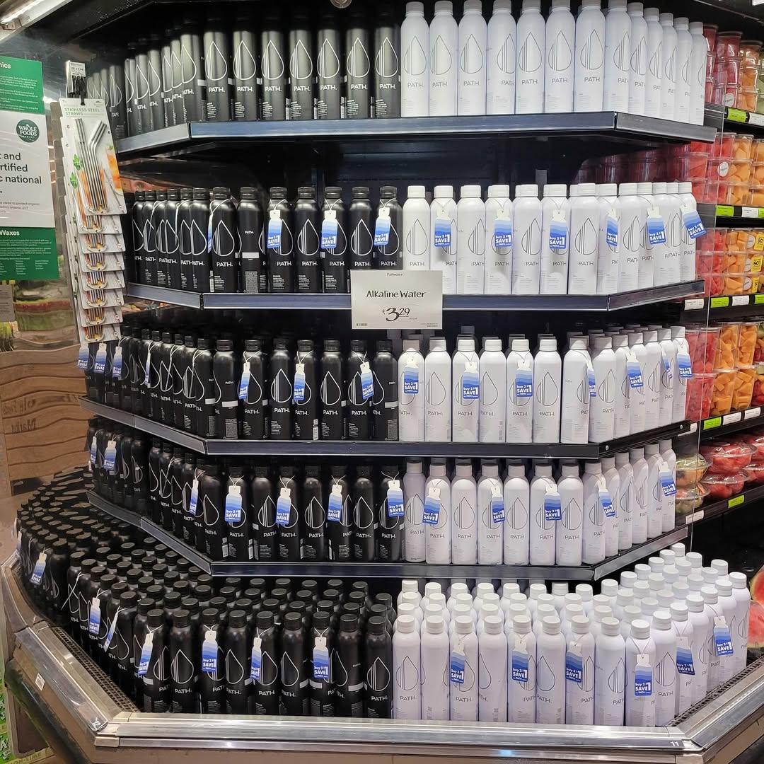 PATH aluminum water bottles displayed on a multi-tier supermarket endcap, black and white refillable bottles stacked