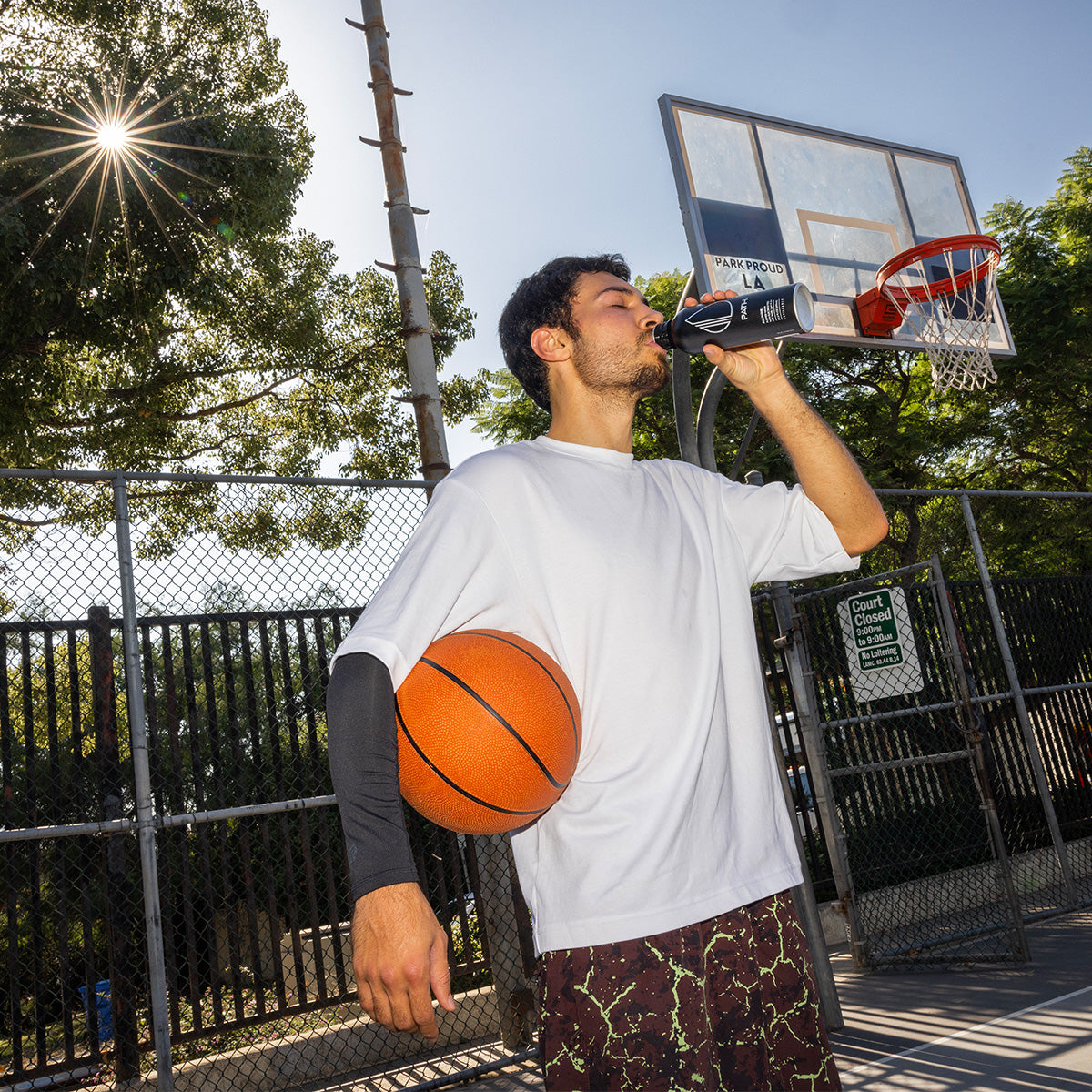 man playing basketball drinking an alkaline path water bottle