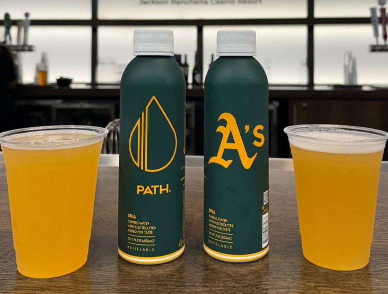 Front view of customized aluminum bottled water bottles showcasing PATH and A’s designs with drinks on a countertop